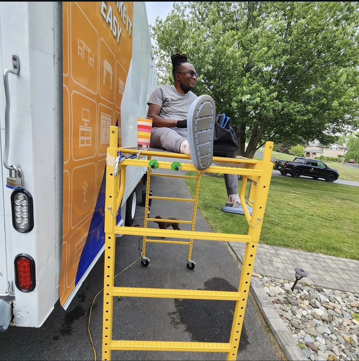 It’s Time Graphics installer on yellow scaffolding beside a box truck getting an orange wrap