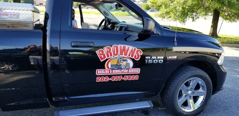 Black pickup truck with a hauling company door logo