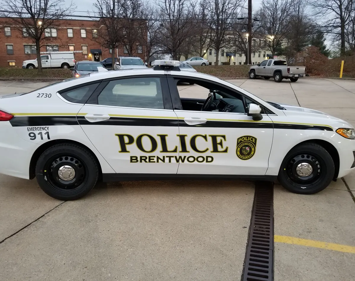 White patrol sedan with black and gold police graphics